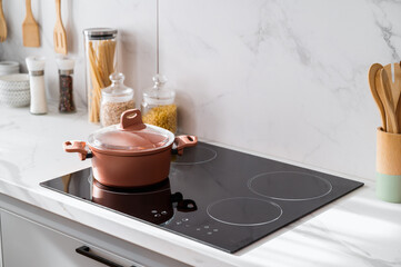 Clean black induction stove with control panel near marble countertop - obrazy, fototapety, plakaty