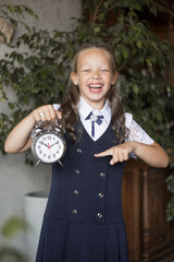 Schoolgirl, in school uniform, with clock. Back to school concept.