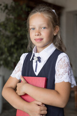 Primary schoolgirl, in school uniform, with a book.

