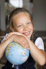 Primary schoolgirl, in school uniform, with a globe.