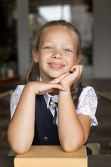 Primary schoolgirl, in school uniform, with a book.

