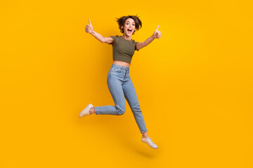 Full size photo of optimistic overjoyed girl dressed jeans khaki top jump show thumbs up approve...
