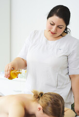 Obraz na płótnie Canvas masseur pours massage oil close-up on the patient's back. Relaxing massage