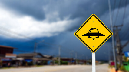 Graphic of UFO on yellow sign on blurred background to warn traffic to aware of UFO