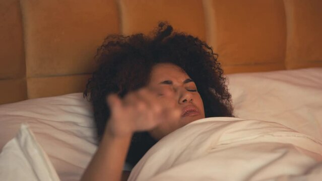 Hungover African American woman waking up in bed after party, having migraine