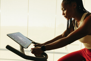 African American woman using a fitness app for an exercise bike workout