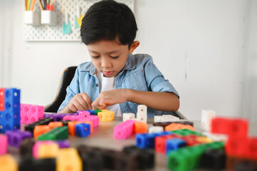 Asian Young Child Playing Colorful Plastic Cubes on Desk at Home. Learning and Education on Counting Cube in Math, Develop the Brain and Meditation while Playing.