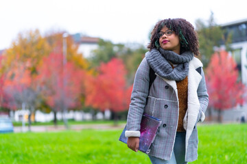 Portrait of black ethnic girl in college in autumn with college in background, back to school