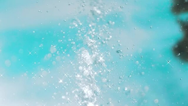 Water from a fountain sparkling and forming drops in the sky on a summer day in slow motion
