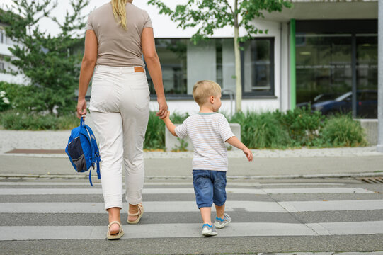 Mother and toddler son crossing the street on the crosswalk