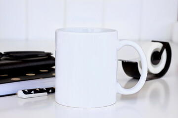 11 oz white coffee mug mock up with black office accessories. Template space for creative design