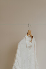 Wrinkled white female blouse, shirt on hanger. Minimalist essential fashion clothes