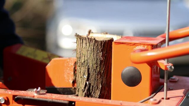 Hydraulic wood splitter cutting wood on a sunny day. 4K Video