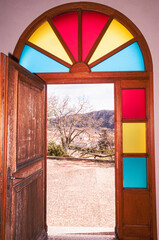 Front view, medium distance of, an open front door, with colorful glass panels, surrounding the door frame to, a french chateau, tasting room