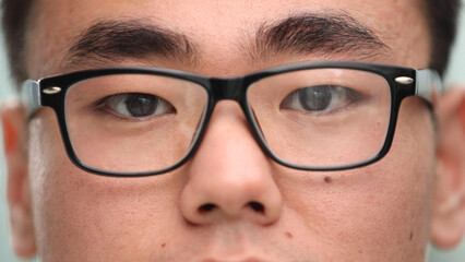 Close-up of a focused Asian businessman, wears glasses to reduce eye strain - obrazy, fototapety, plakaty