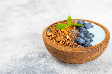 Useful breakfast. Granola bowl with yogurt and fresh berries on a textured kitchen table.Acai and spirulina bowl.Bowl of Greek yogurt with granola, almonds, blueberries, raspberries and strawberries.