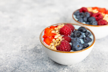 Useful breakfast. Granola bowl with yogurt and fresh berries on a textured kitchen table.Acai and spirulina bowl.Bowl of Greek yogurt with granola, almonds, blueberries, raspberries and strawberries.