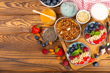 Granola bowl with yogurt and fresh almonds, blueberries, raspberries,peach and strawberries on a brown kitchen table.Acai and spirulina bowl.Healthy breakfast concept.