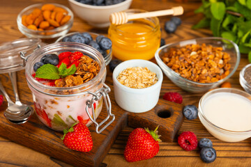 Granola bowl with yogurt and fresh almonds, blueberries, raspberries,peach and strawberries on a brown kitchen table.Acai and spirulina bowl.Healthy breakfast concept.
