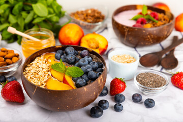 Granola bowl with yogurt and fresh almonds, blueberries, raspberries,peach and strawberries on a marble kitchen table.Acai and spirulina bowl.Healthy breakfast concept.copy space.Place for text.