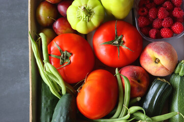 Wooden crate full of healthy seasonal fruit and vegetable. Top view, dark background.