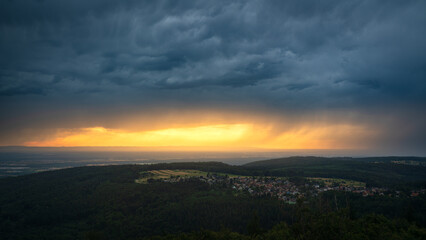 Golden sunset over the upper Rhine plain while a summer thunderstorm passes over the northern Black Forest