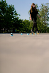 sporty girl practicing tricks on roller skates in park on city background enjoying roller skating lesson with chips close-up Street sports concept