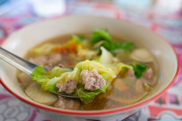 Thai style soup with pork and vegetable in bowl.