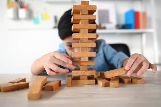 Child Boy Playing Jenga Game Exciting on Desk at Home. Unleashing Fun and Skill. Careful and Attentive Keeping, Concentrate and Slowly Take It Out while Playing. Study and learn to balance objects.