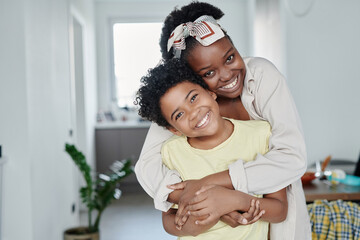 Portrait of happy mom embracing her little son and they smiling at camera together at home