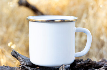 Blank white enamel coffee cup mockup, camping mug in forest.