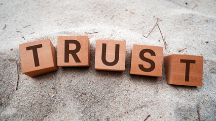 Trust symbol in wooden cubes. Sand background. Business and Trust Concept.