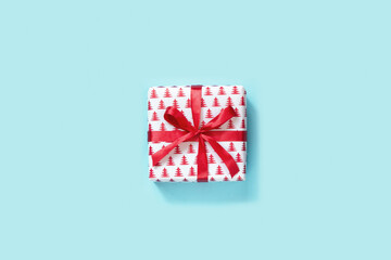 Christmas white gift with red ribbon on blue background. Xmas holiday. Boxing day. View from above.
