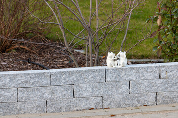 2 small white frog figures sitting on a wall