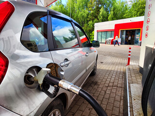 Gasoline filling station, car, and fuel nozzle inserted into the fuel tank. Refueling a car with...