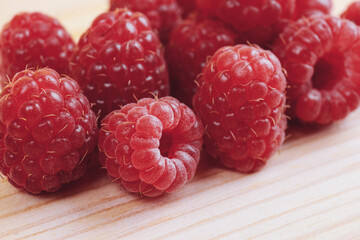Heap of fresh ripe and sweet raspberries on wooden table. Red raspberries. Macro shot.