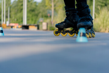 Obraz premium sporty girl practicing tricks on roller skates in park on city background enjoying roller skating lesson with chips close-up of street sport