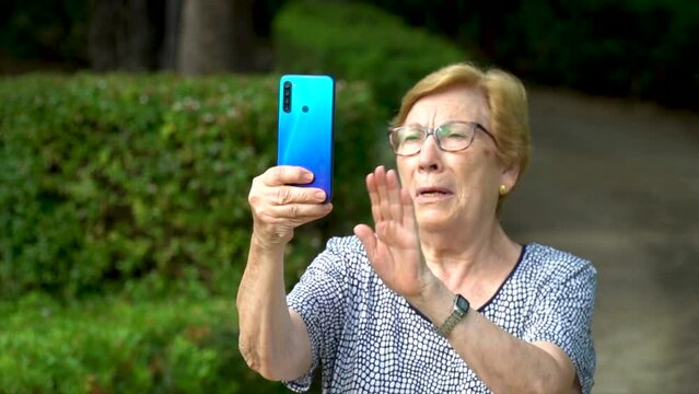 Slow motion, happy senior woman recording a video selfie outdoors