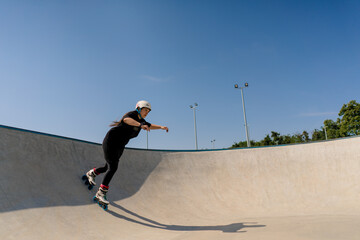 young skilled woman rollerblading and jumping on the ramp in the skate park outside Practicing her...