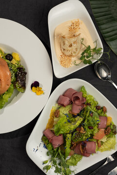 Variety of meals in white plates soup and beef salad and salmon salad top view 