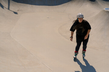 young skilled woman rollerblading and jumping on the ramp in the skate park outside Practicing her...
