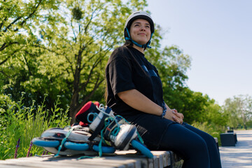Naklejka premium portrait of a young smiling hipster girl in a skate park wearing a protective helmet before starting to skate roller skates in the background