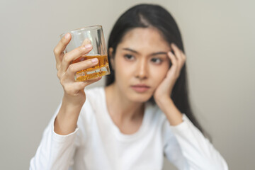 Alcoholism drunk, sad asian young woman hand holding glass of alcohol or whiskey, alone depressed female drink booze on background. Treatment of alcohol addiction, suffer abuse problem alcoholism.