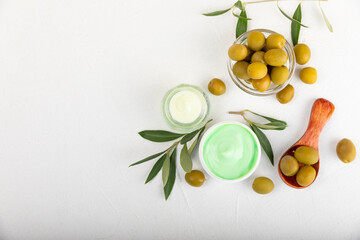 Natural spa.Olive natural cream and olive berries on a light textural background.Olive cream for hands, body and face. Concept of natural ingredients in cosmetology for gentle skin care.Spa care.