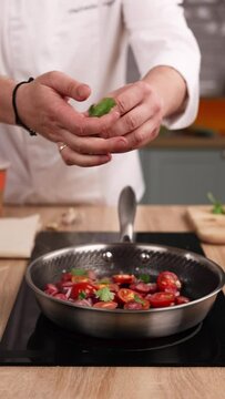 Chef prepares a delicious dish with tomatoes in the kitchen. Close-up