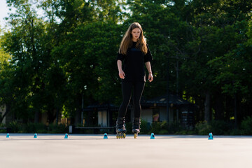sporty girl practicing tricks on roller skates in park on city background enjoying roller skating...