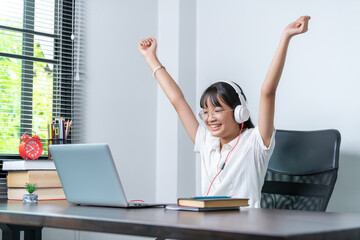 Happy smiling female student wearing headphones talking in online discussion meeting using laptop in home office. female college student studying distance education business