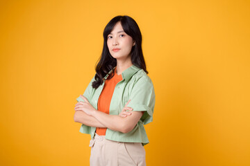 Radiate confidence portrait of young Asian woman wears pastel green shirt on orange shirt confidently crossing her arms. Perfect for capturing a sense of self assurance and empowerment.