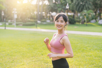Capture the happiness of a young, beautiful Asian woman in her 30s as she smiles and looks at the camera in a park at sunset. Experience the concept of wellness living.
