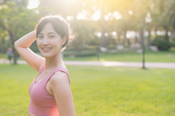 Experience the joy of wellness living as a happy, beautiful Asian woman in her 30s smiles and looks at the camera in a park at sunset.